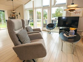 Una sala de estar moderna con un sofá, televisor y una mesa con un florero y control remoto.