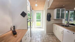 A modern kitchen with white cabinets, a wooden countertop, and a tiled floor. - 9 Person Holiday Home in Saeby (Sæby)