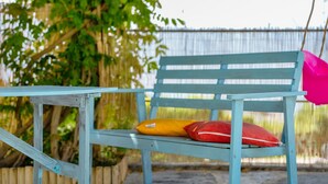 A wooden bench with a metal frame, two cushions, and a metal fence in the background. - Apartment 'Casa Mike' with Lake View, Private Garden and Wi-Fi (Colico)
