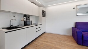 A modern kitchen with white cabinetry, a built-in microwave, and a coffee machine. - Apartment 'Casa Mike' with Lake View, Private Garden and Wi-Fi (Colico)