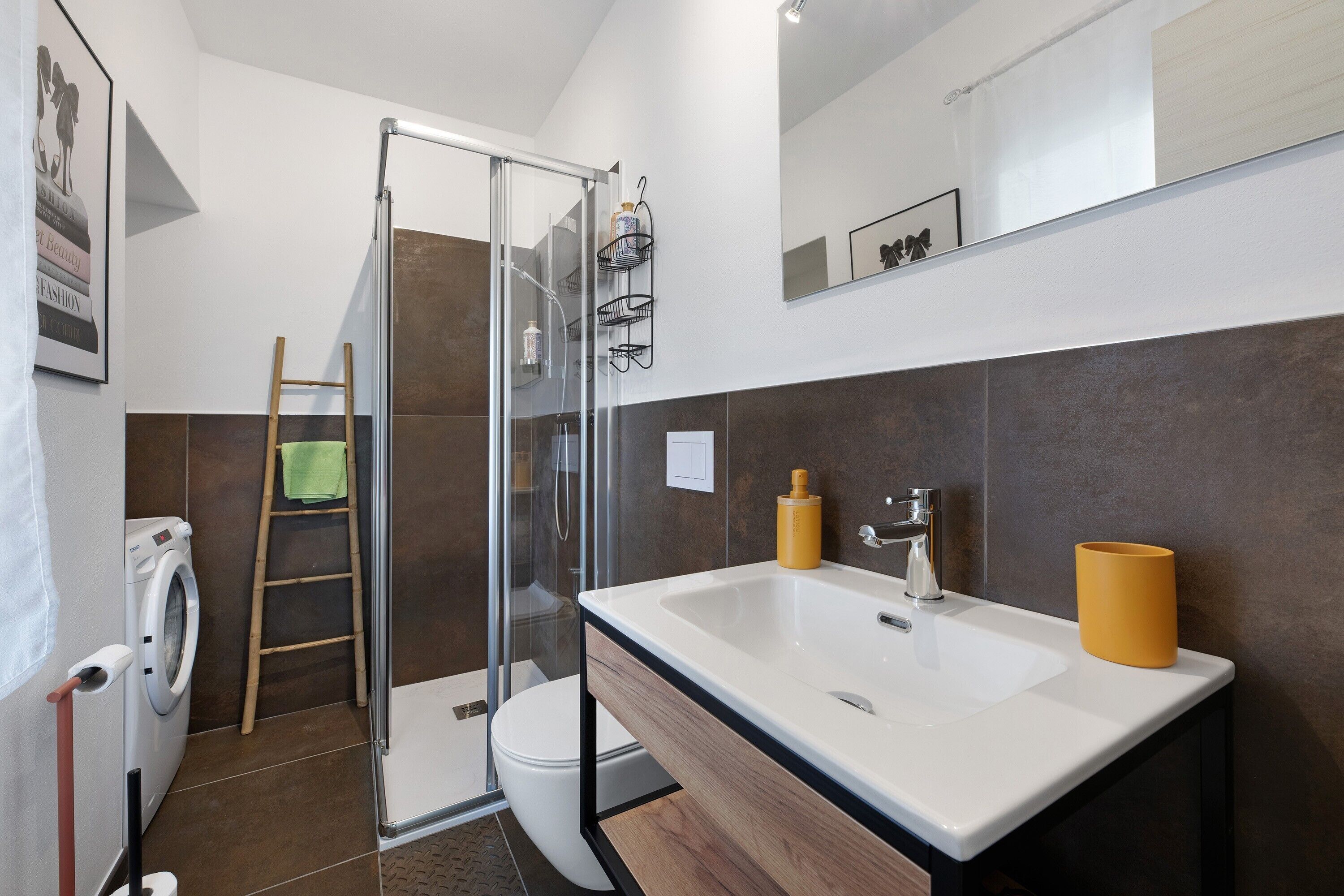 Un baño moderno con cabina de ducha de vidrio, inodoro, lavadora y lavabo con dos dispensadores de jabón.