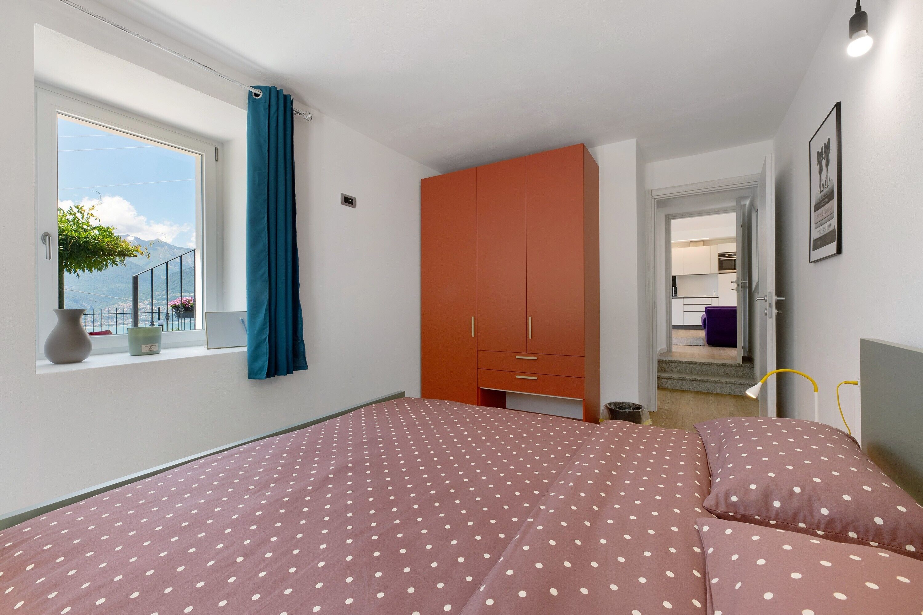 Un dormitorio con cama, ventana con vistas y un armario naranja.