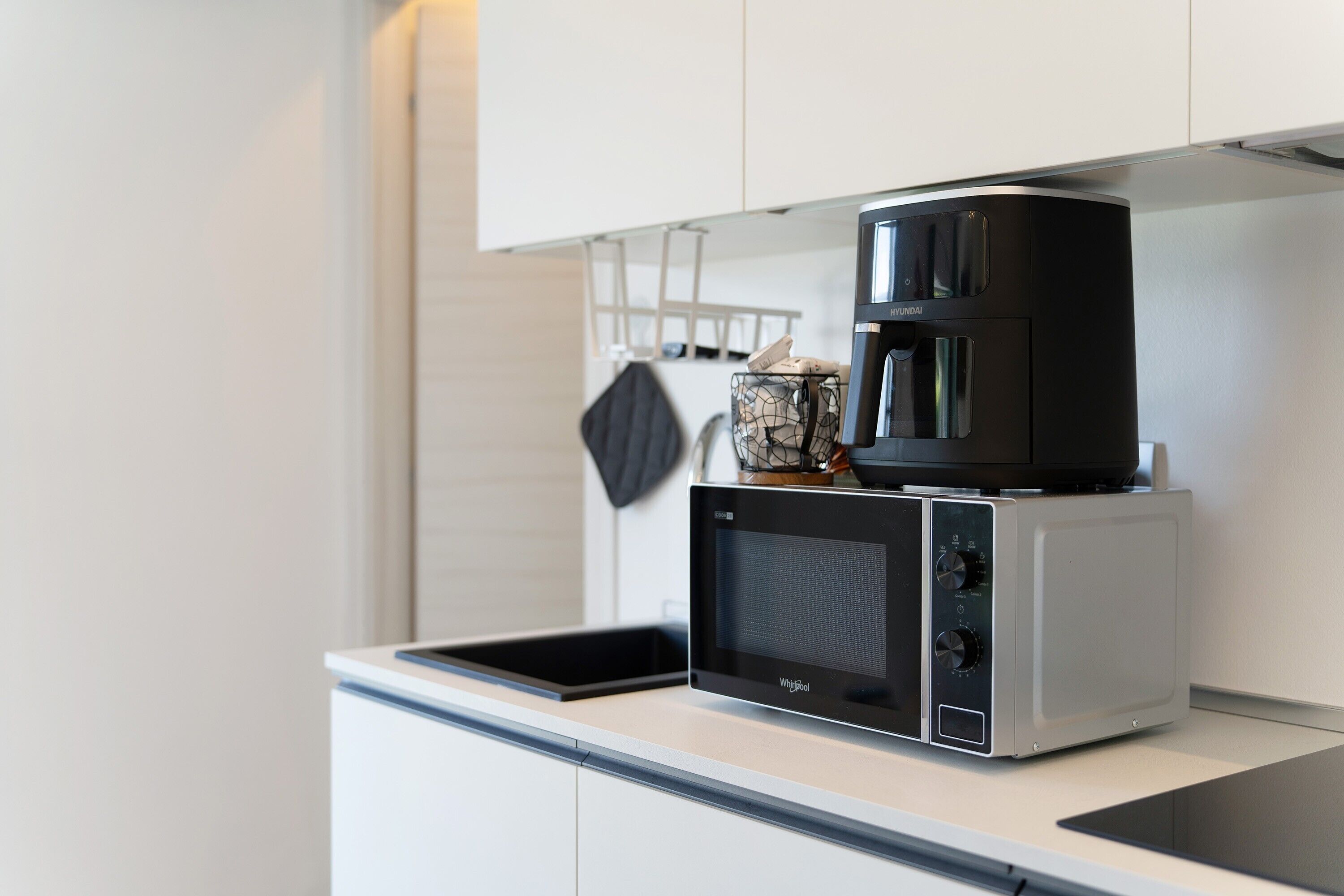Cocina compacta con cafetera y microondas sobre una encimera.