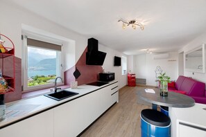 A modern kitchen with a view of a lake, a dining area with a pink sofa, and a small table.