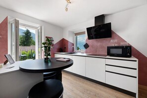 A modern kitchen with a dining area, a black microwave, and a Samsung TV.