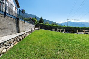 A stone wall with a metal railing, a grassy lawn, and a wooden fence.
