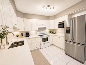 A modern kitchen with white cabinetry, stainless steel appliances, and a built-in microwave.