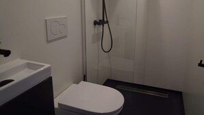Un bagno piccolo con il water bianco, uno spazio doccia e un lavandino.