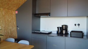 Una cucina moderna con mobili grigi, una macchina da caffè in acciaio inossidabile e un piccolo piano di lavoro.