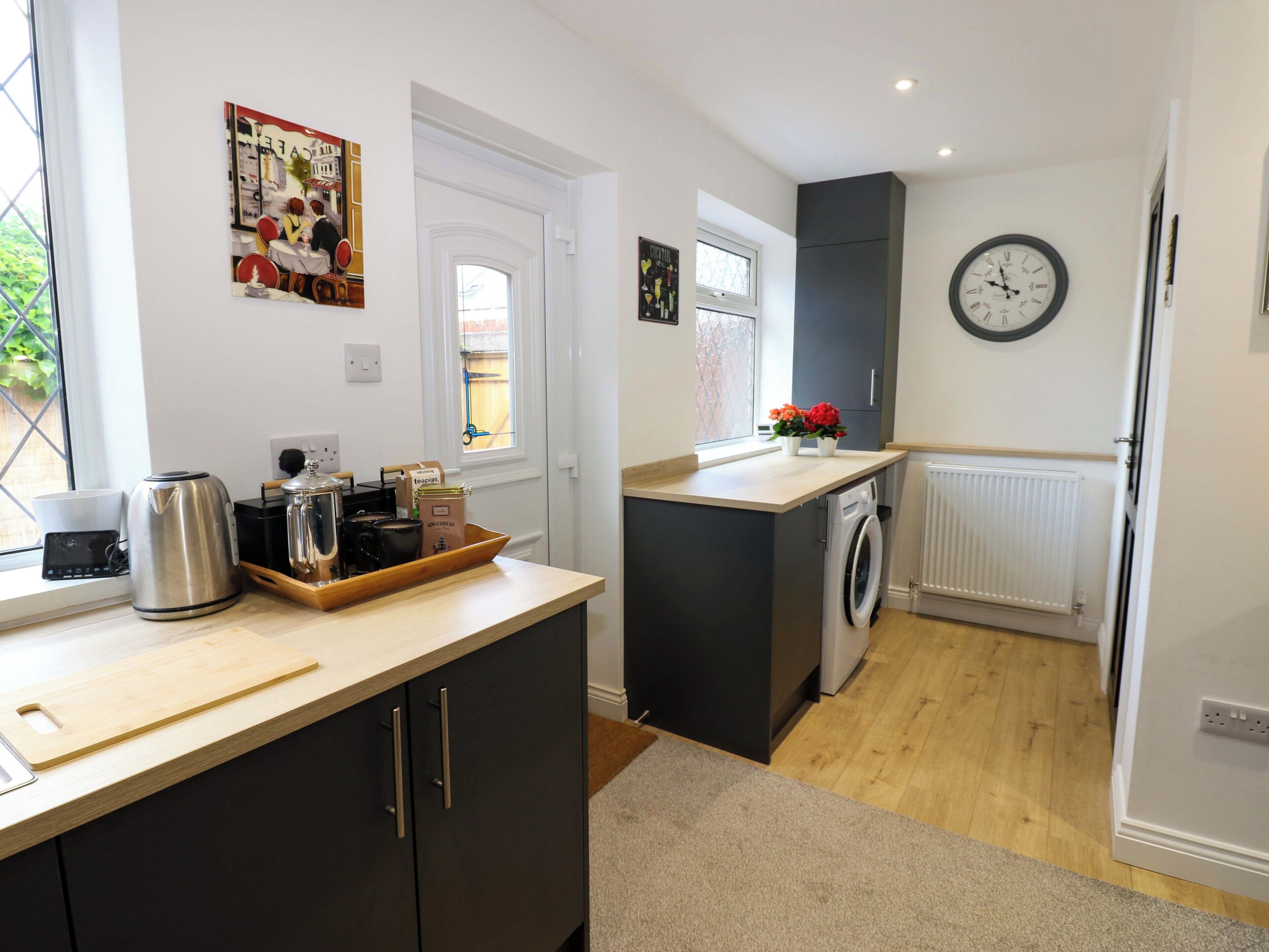 A compact kitchen with a washing machine, a kettle, and a coffee maker on the counter.