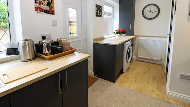 A compact kitchen with a washing machine, a kettle, and a coffee maker on the counter. - 8 Percy Terrace (Sunderland)