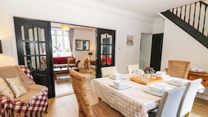A dining area with a table set for four, a wicker chair, and a checkered sofa. - 8 Percy Terrace (Sunderland)