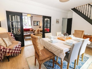 A dining area with a table set for four, a wicker chair, and a checkered sofa. - 8 Percy Terrace (Sunderland)