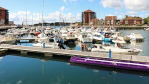 A marina with multiple boats docked, a wooden pier, and buildings in the background. - 8 Percy Terrace (Sunderland)