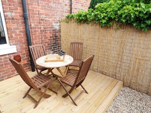 A wooden deck with a round table and four chairs, a brick wall, and a bamboo fence. - 8 Percy Terrace (Sunderland)