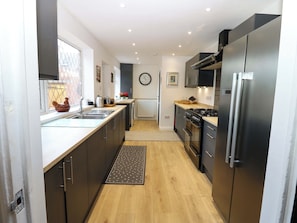 A modern kitchen with dark cabinetry, stainless steel appliances, a wooden countertop, and a visible clock on the wall. - 8 Percy Terrace (Sunderland)
