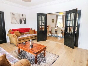Een woonkamer met een bank, een salontafel en een open deur naar een eetruimte.