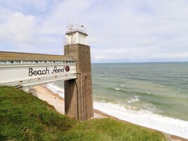 Un puente con señalización que indica 'Beach Food', vista costera y una zona ajardinada.