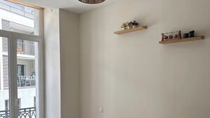 A bedroom with a bed, pillows, a hanging light fixture, and two wooden shelves with items. - Apartment in the heart of Annonay (Annonay)