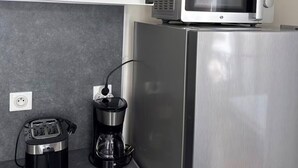 A kitchen with a microwave on a cabinet, a coffee maker, and a toaster on the counter. - Apartment in the heart of Annonay (Annonay)