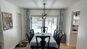 A dining area with a table, chairs, a hanging light fixture, and a view through a window. - Cozy, newly renovated home with a gorgeous fireplace and office space. (Midland)