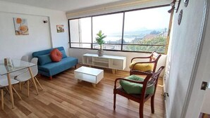 Ein Wohnzimmer mit Glastisch, blauem Sofa, weißem Couchtisch und Holzstühlen.
