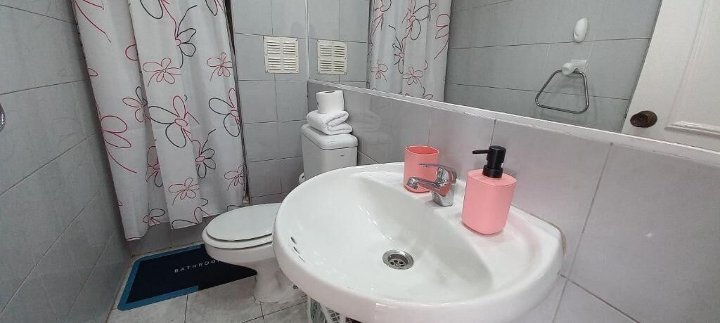 A bathroom with a toilet, sink, and shower curtain.