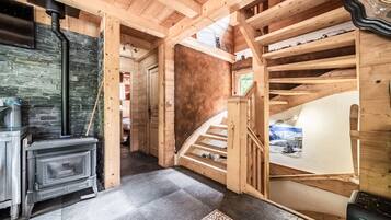 Un intérieur en bois avec une cheminée, un escalier et une vue sur l’extérieur.