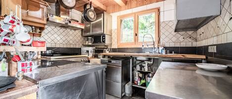 A modern kitchen with stainless steel appliances, wooden cabinets, and a window providing natural light.