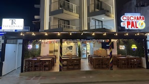 Un edificio moderno con un restaurante llamado 'Cuchara de Palo' y un letrero del 'Tayronaka Hotel'.