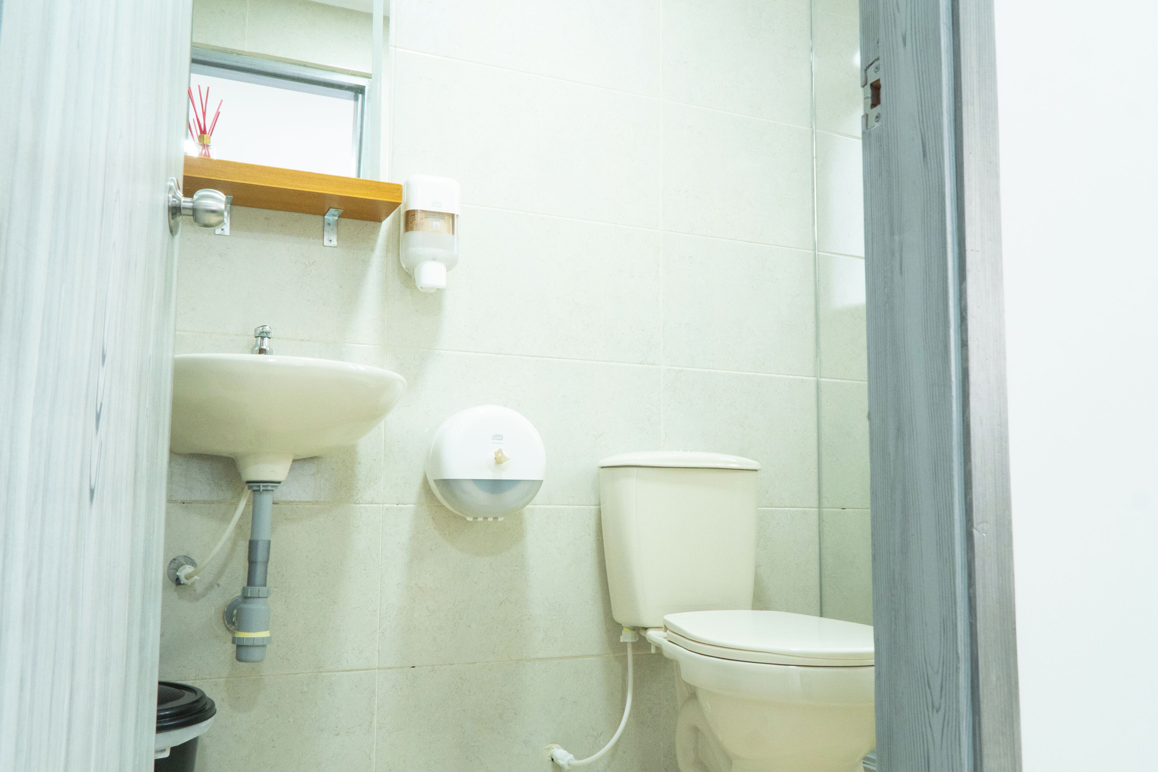 A bathroom with a toilet, sink, and a hand dryer mounted on the wall.