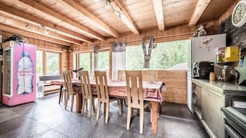 Un intérieur en bois comprenant une table à manger, des chaises, un réfrigérateur et un distributeur d’eau.