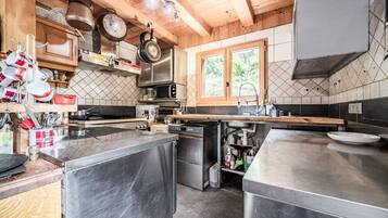 Une cuisine moderne dotée d’appareils électroménagers en acier inoxydable, de meubles en bois et d’une fenêtre laissant entrer la lumière naturelle.