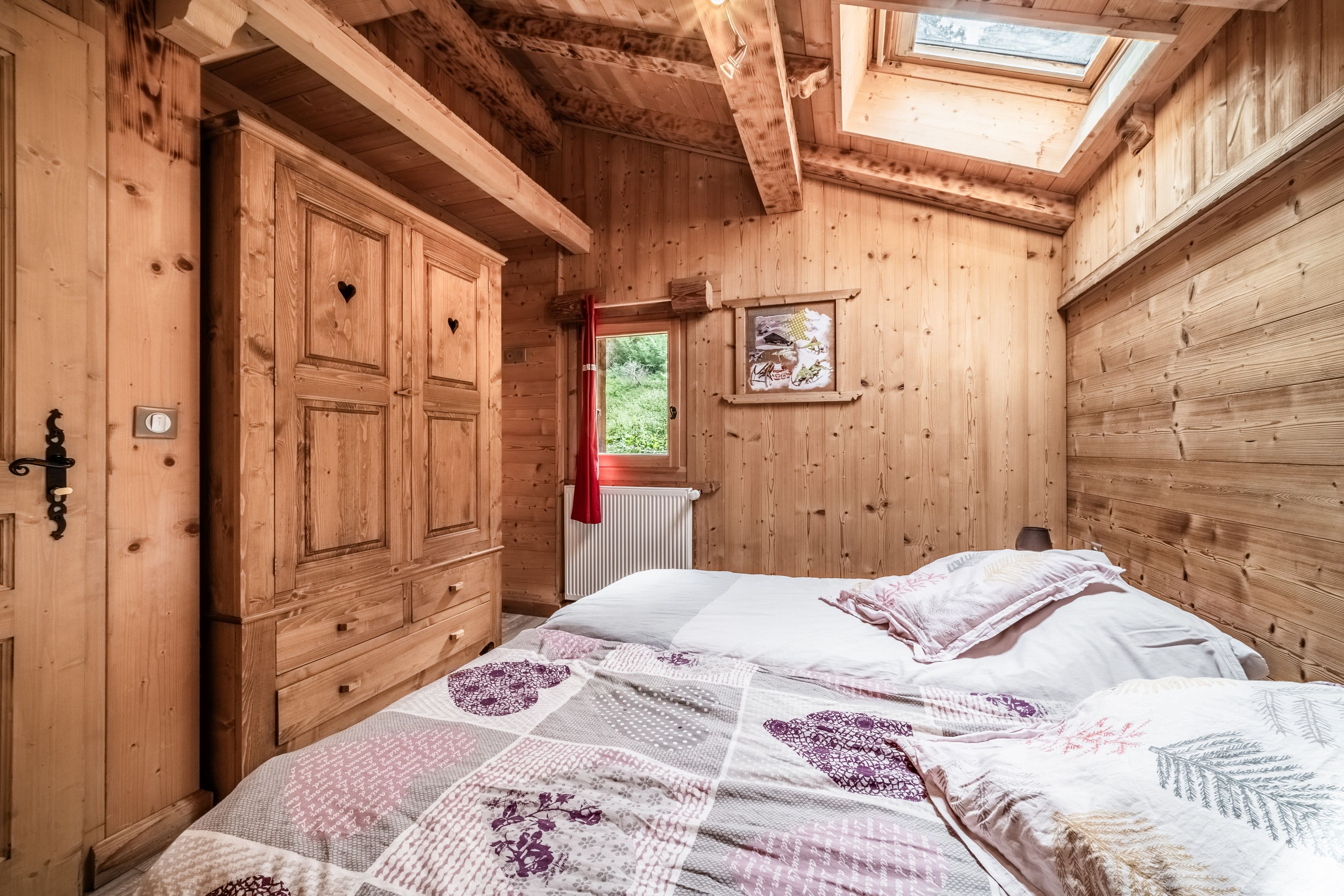 Una habitación de madera con cama, ventana y radiador.