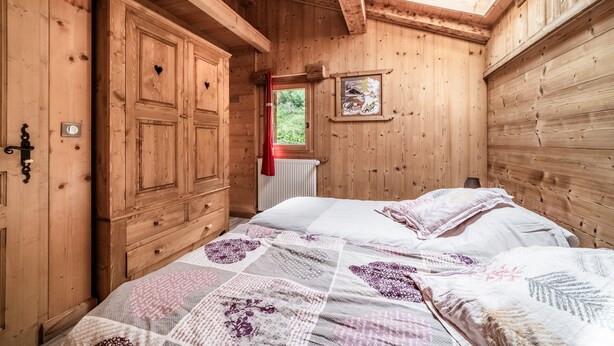 A wooden room with a bed, a window, and a radiator.