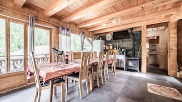 L’intérieur d’un chalet en bois comprend un coin repas, une cuisine et une grande fenêtre donnant sur une forêt.