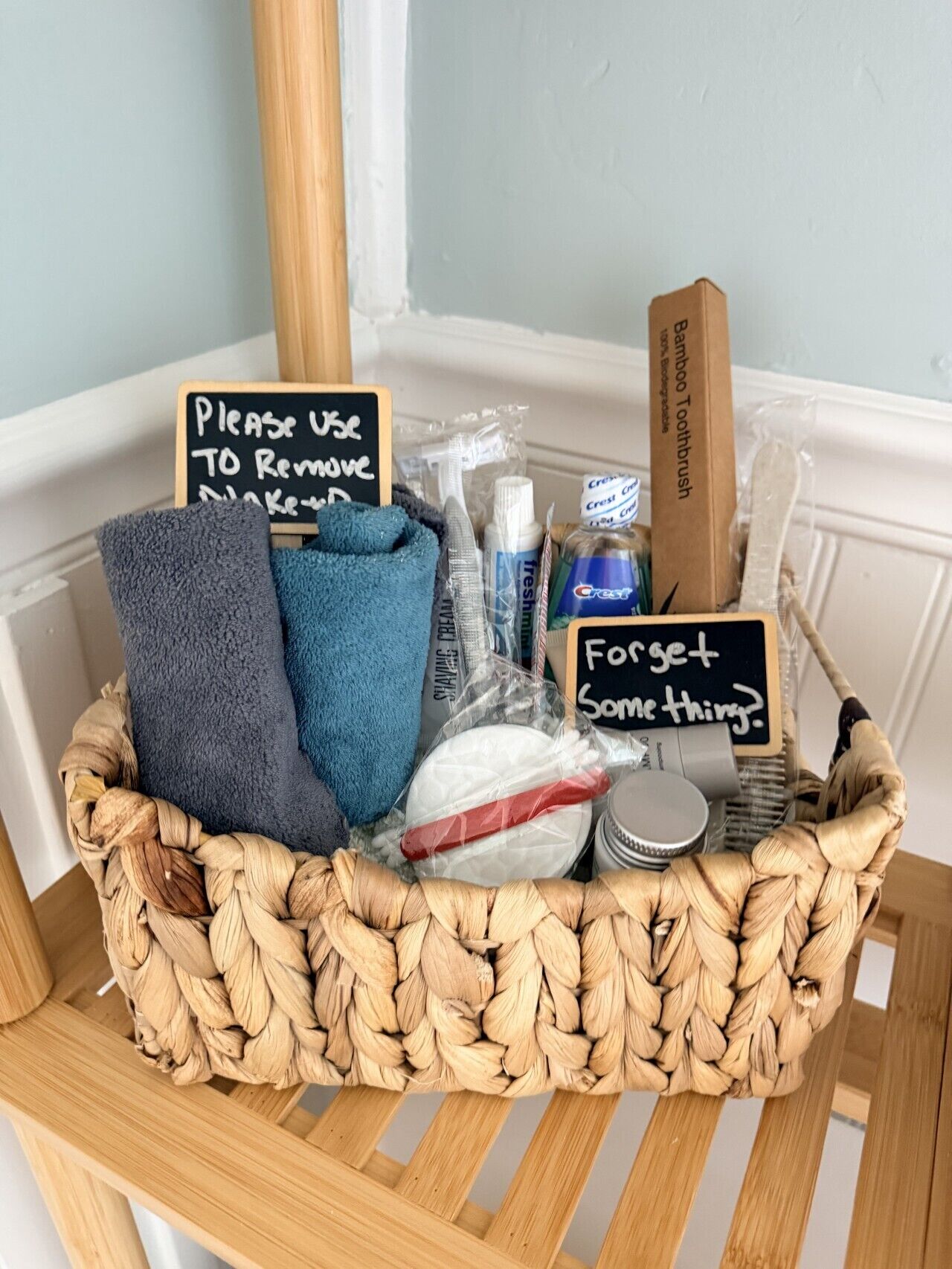 Un panier en osier contenant des articles de toilette et une pancarte indiquant qu’il faut utiliser ces articles pour enlever le maquillage.