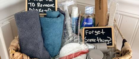 Un panier en osier contenant des articles de toilette et une pancarte indiquant qu’il faut utiliser ces articles pour enlever le maquillage.