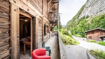 Un bâtiment en bois doté d’un balcon, d’une chaise rouge et offrant une vue sur une montagne.