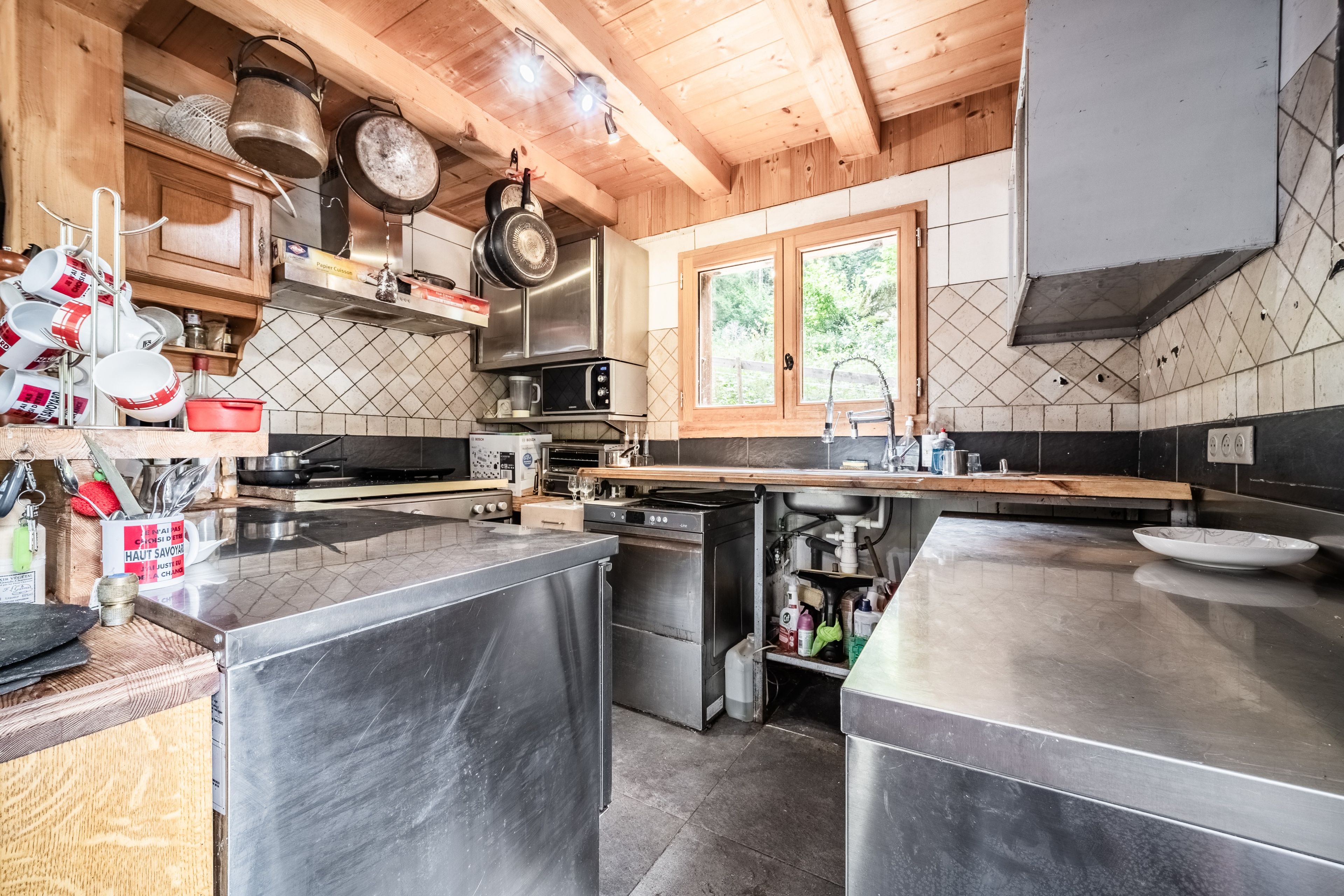 Una cocina moderna con electrodomésticos de acero inoxidable, armarios de madera y un ventanal que proporciona luz natural.