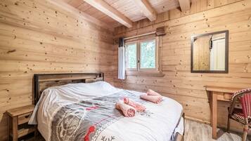 Une pièce dans une cabane en bois, comprenant un lit, une chaise et une fenêtre.