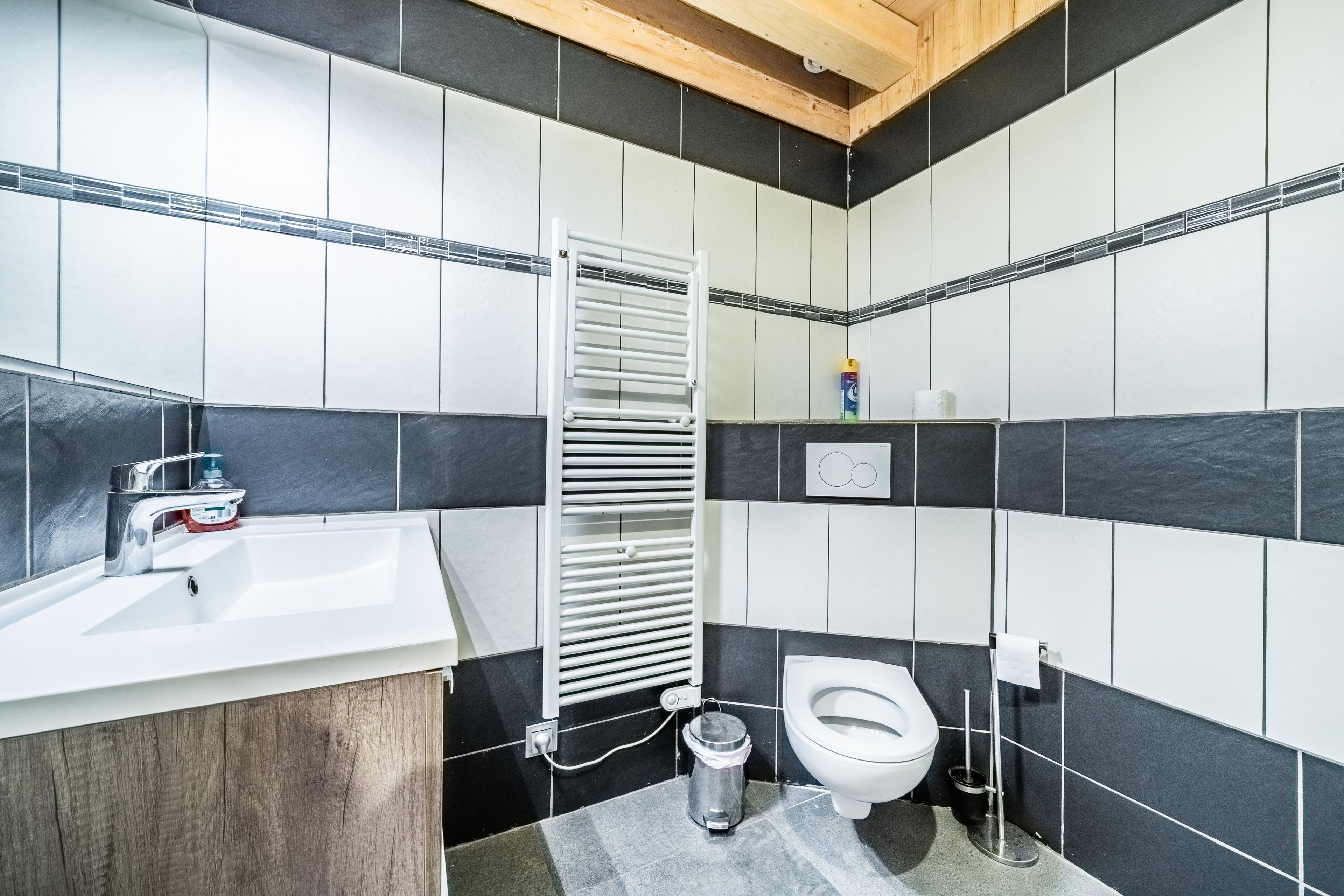 A bathroom with a white sink, a toilet, a towel rack, and a trash bin.