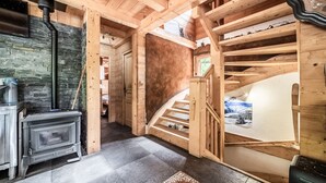 Een houten interieur met een open haard, een trap en uitzicht op de omgeving.