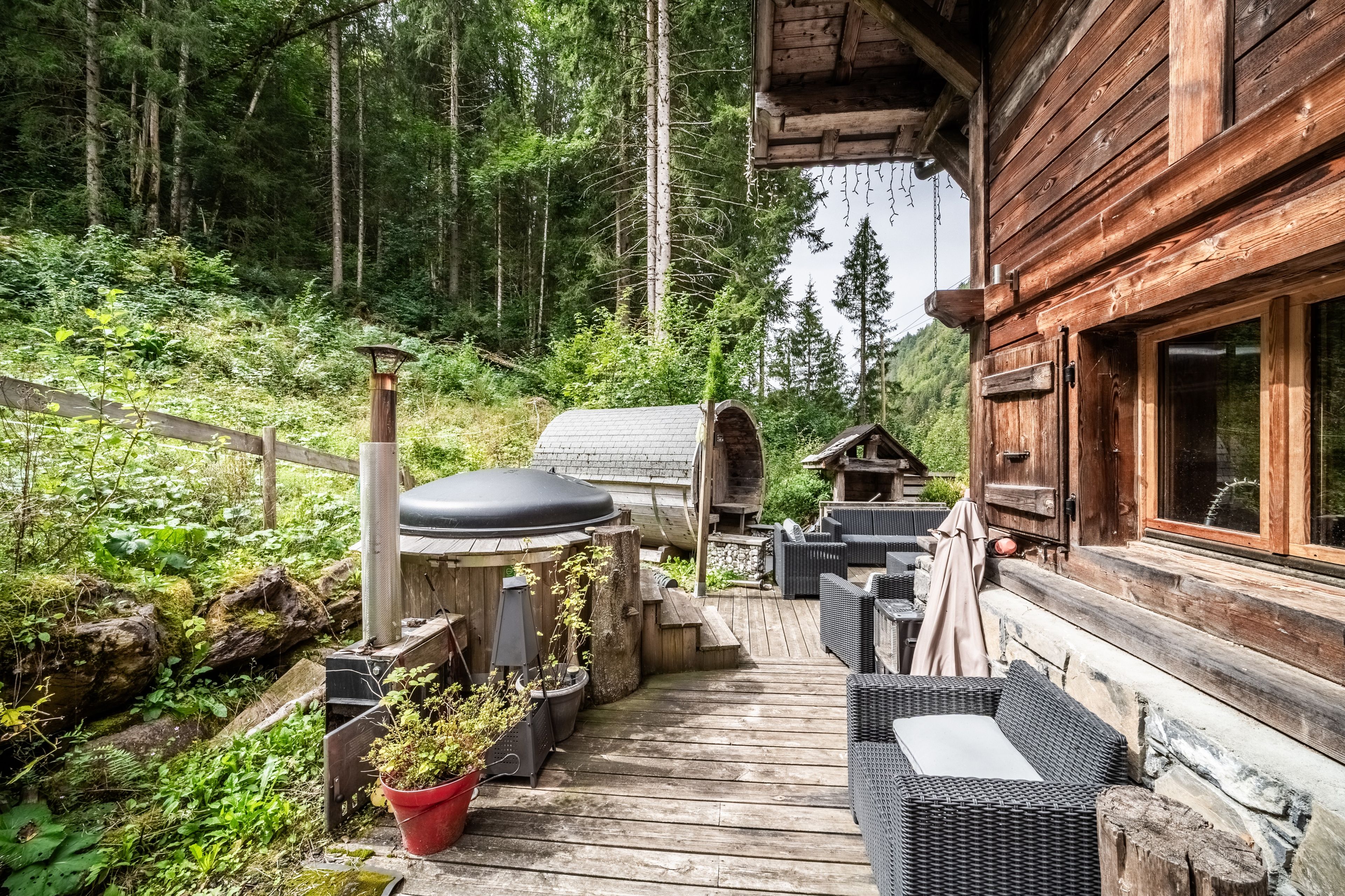 A wooden deck with outdoor furniture, a grill, and a log cabin.