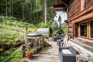 Une terrasse en bois avec des meubles d’extérieur, un barbecue et un chalet en rondins.