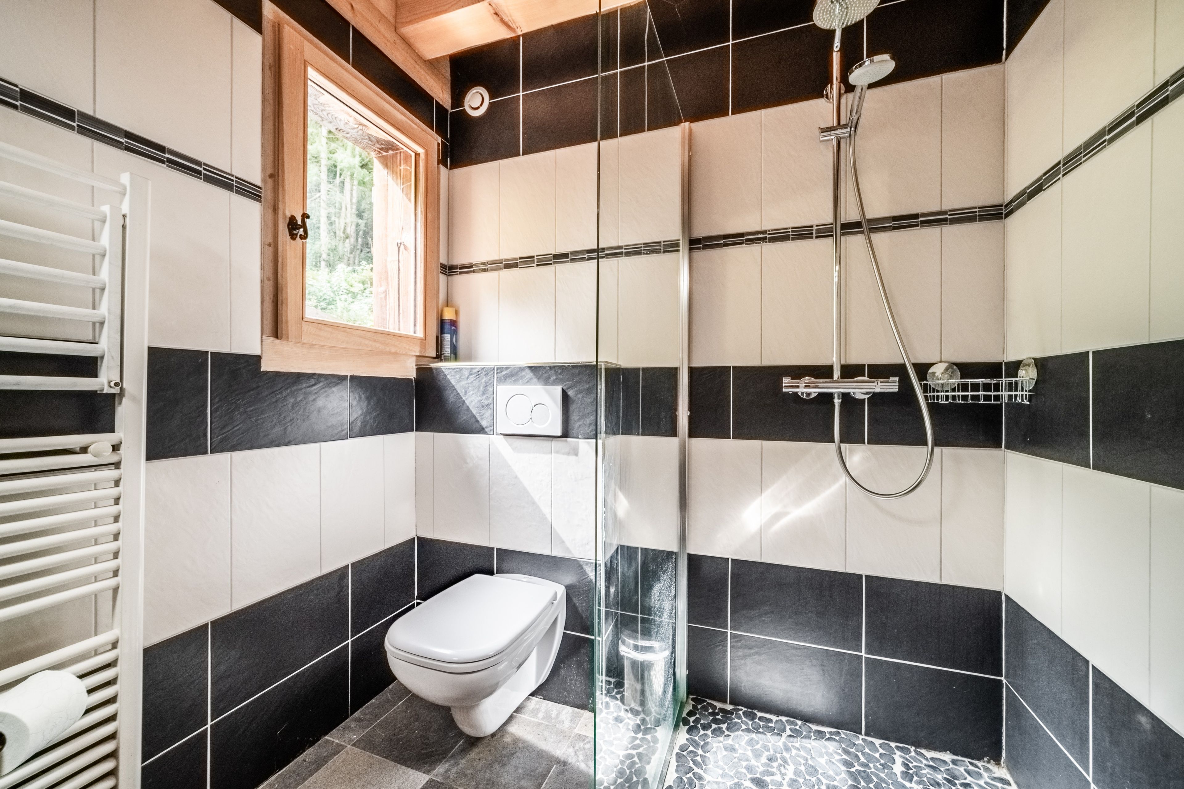 Un baño con inodoro, ducha y ventana.