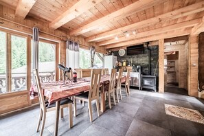 L’intérieur d’un chalet en bois comprend un coin repas, une cuisine et une grande fenêtre donnant sur une forêt.