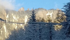 Un paisaje montañoso con árboles cubiertos de nieve y edificios al fondo.
