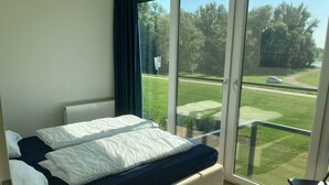 Een slaapkamer met een groot bed, een stoel en uitzicht op een golfbaan.