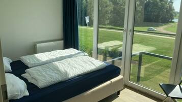 Ein Schlafzimmer mit einem großen Bett, einem Sessel und Blick auf einen Golfplatz.
